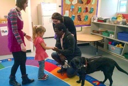 George Stern shakes the hand of a preschool-aged girl.